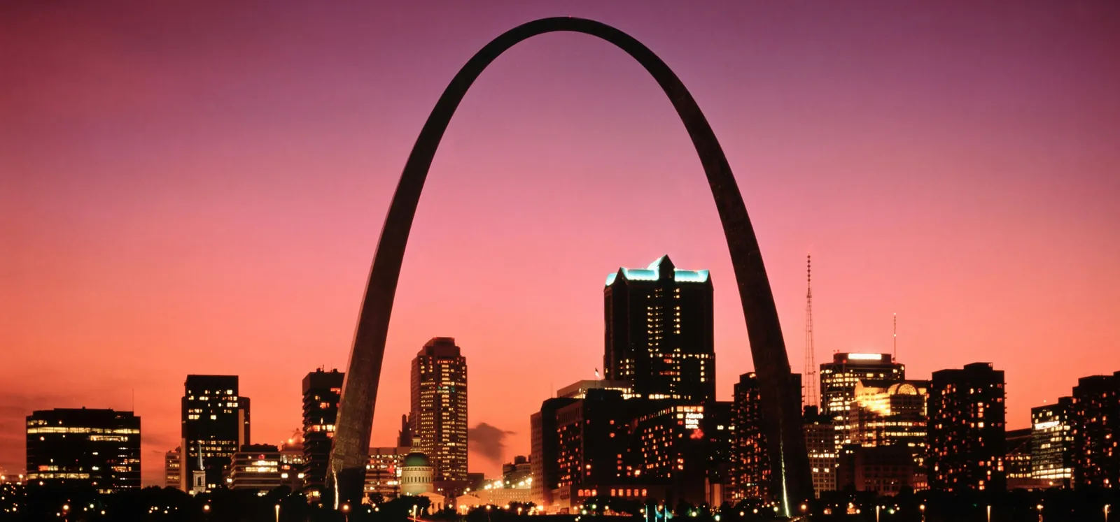 The Gateway Arch over the downtown St. Louis skyline at sunset, seen across the river
