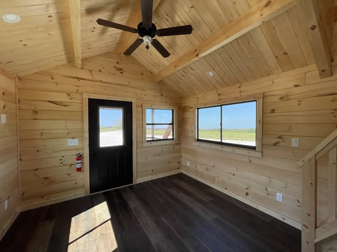 Kodiak living area with ceiling fan, entry door and two windows