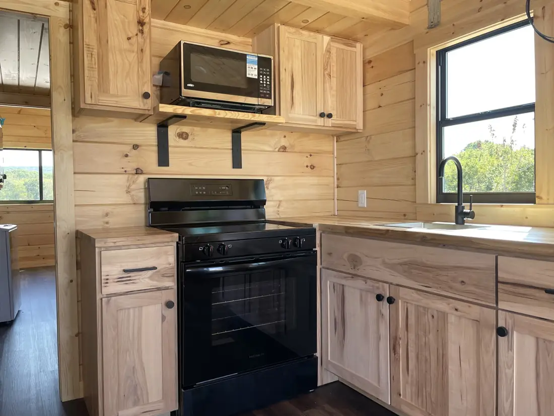 Kodiak kitchen with black range, microwave and hickory cabinets