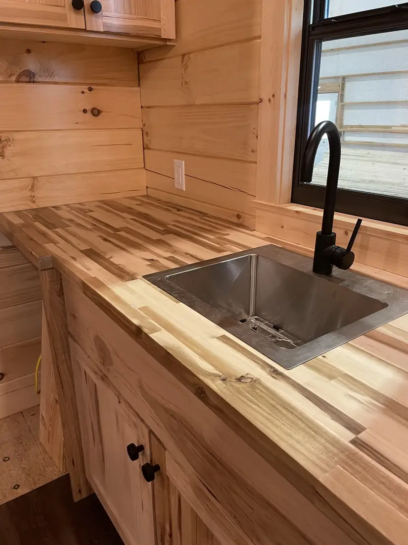 Butcher-block counter with a stainless sink and black faucet