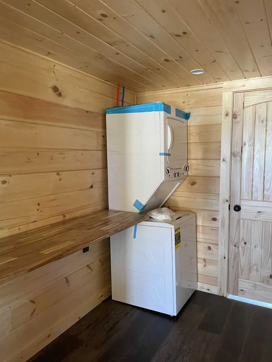 Kodiak laundry nook with a stackable washer and dryer beside a butcher-block shelf
