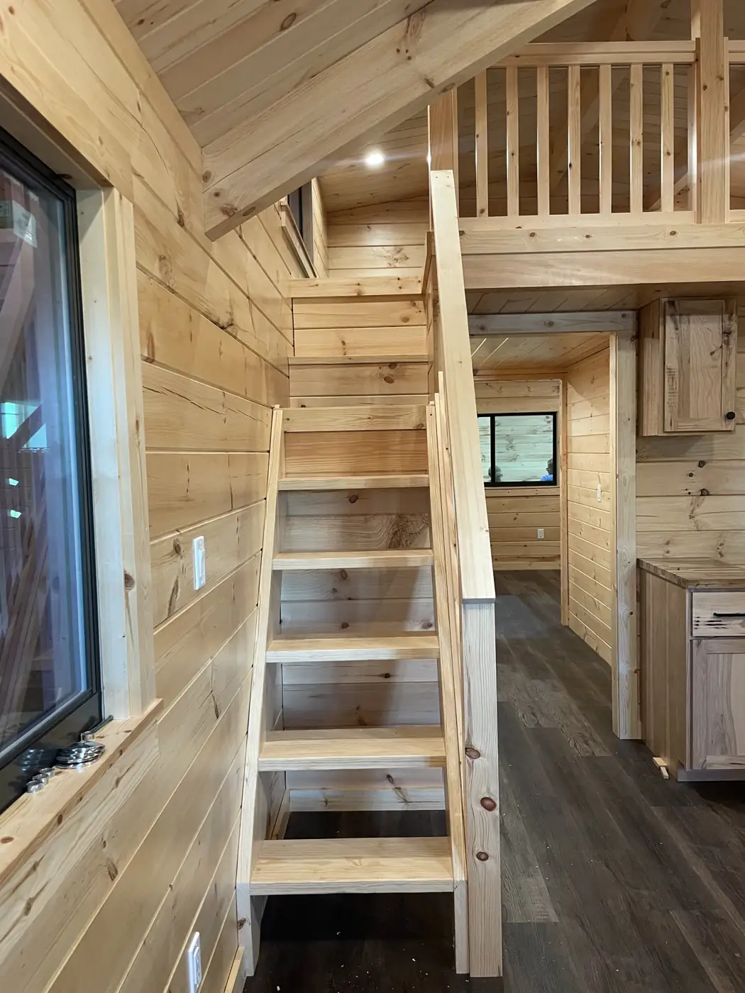 Loft ladder and railing inside the Kodiak with pine walls and a vaulted ceiling