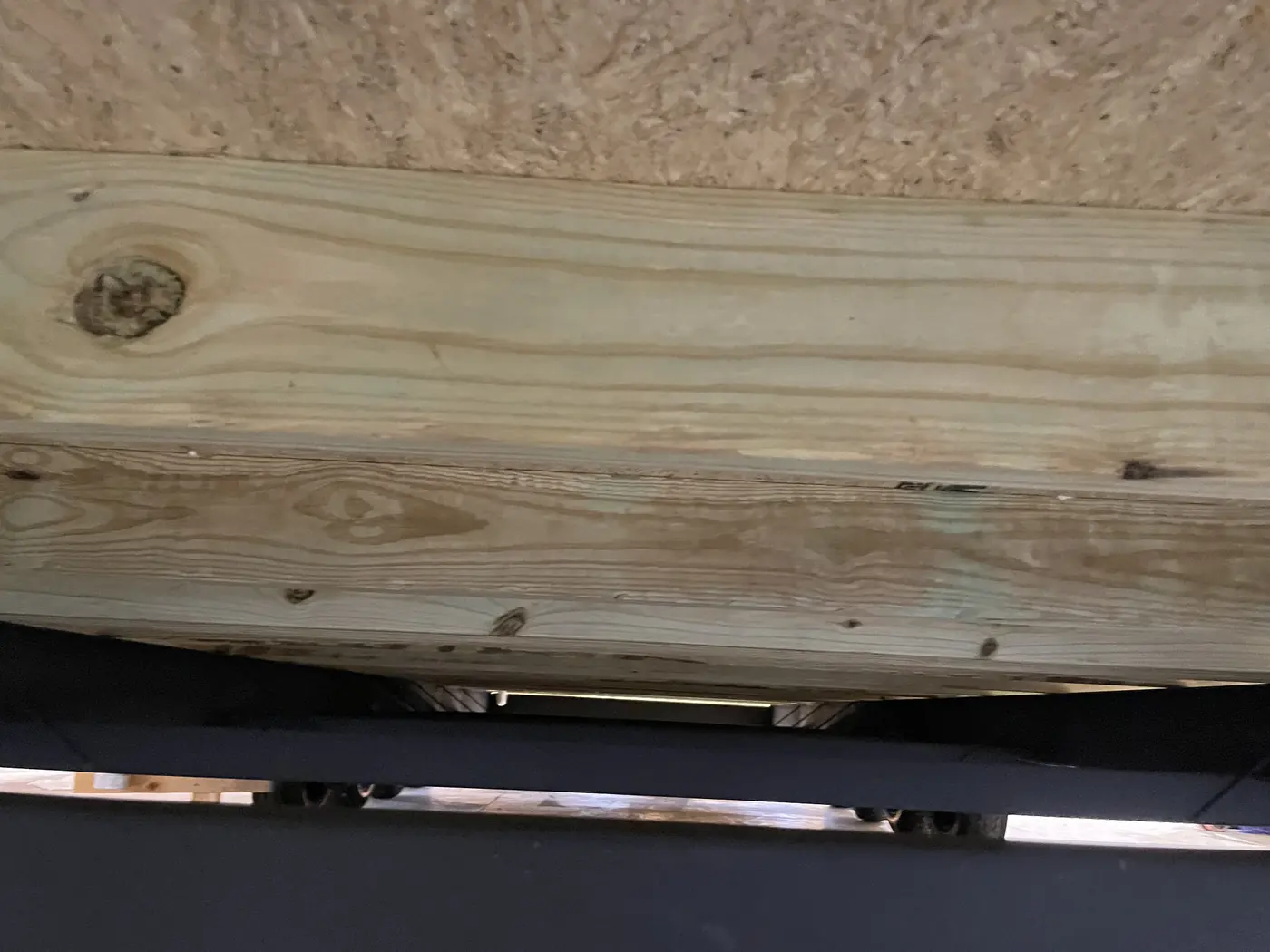 Treated floor joist resting on the steel chassis beam