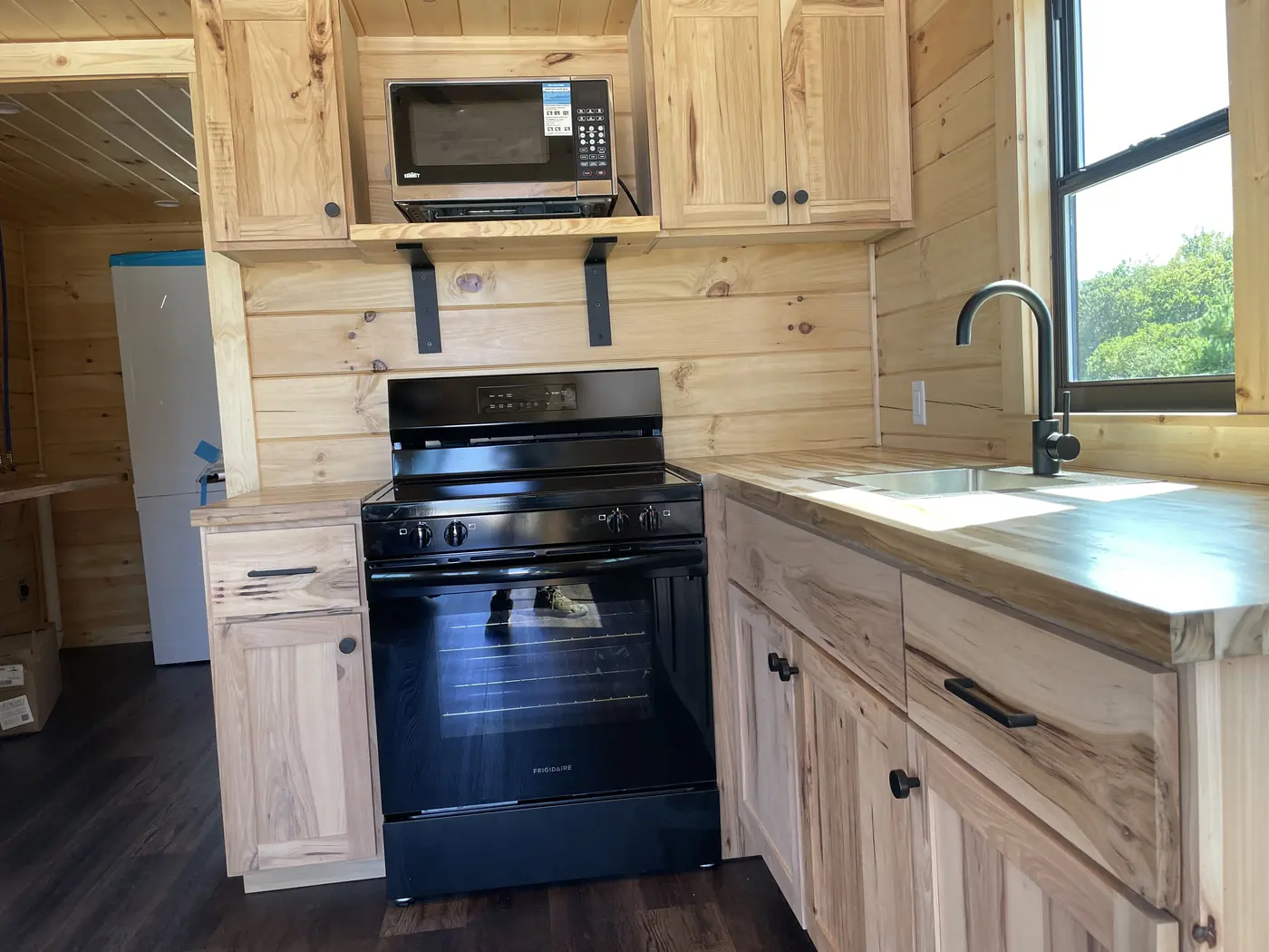 Black electric range between hickory cabinets