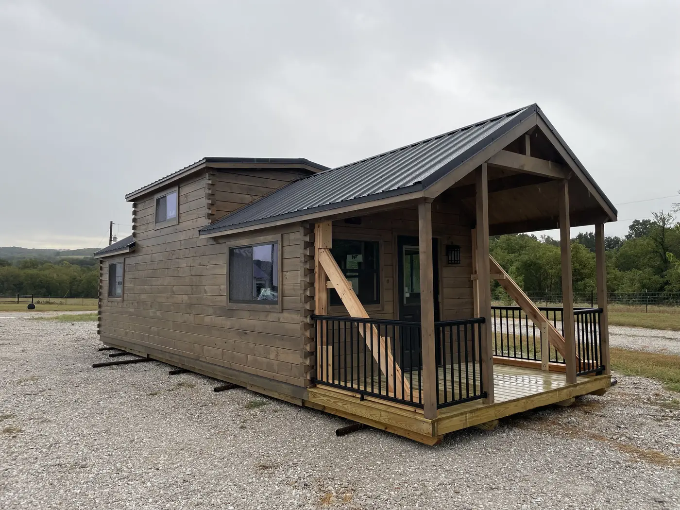 The Kodiak on our lot with stained log walls and a covered front porch