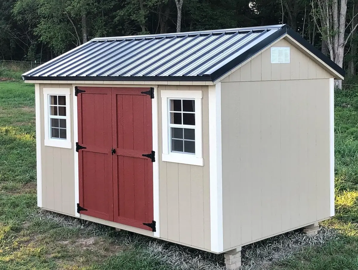 Tan garden shed with red double doors, white-trimmed windows and a black metal roof