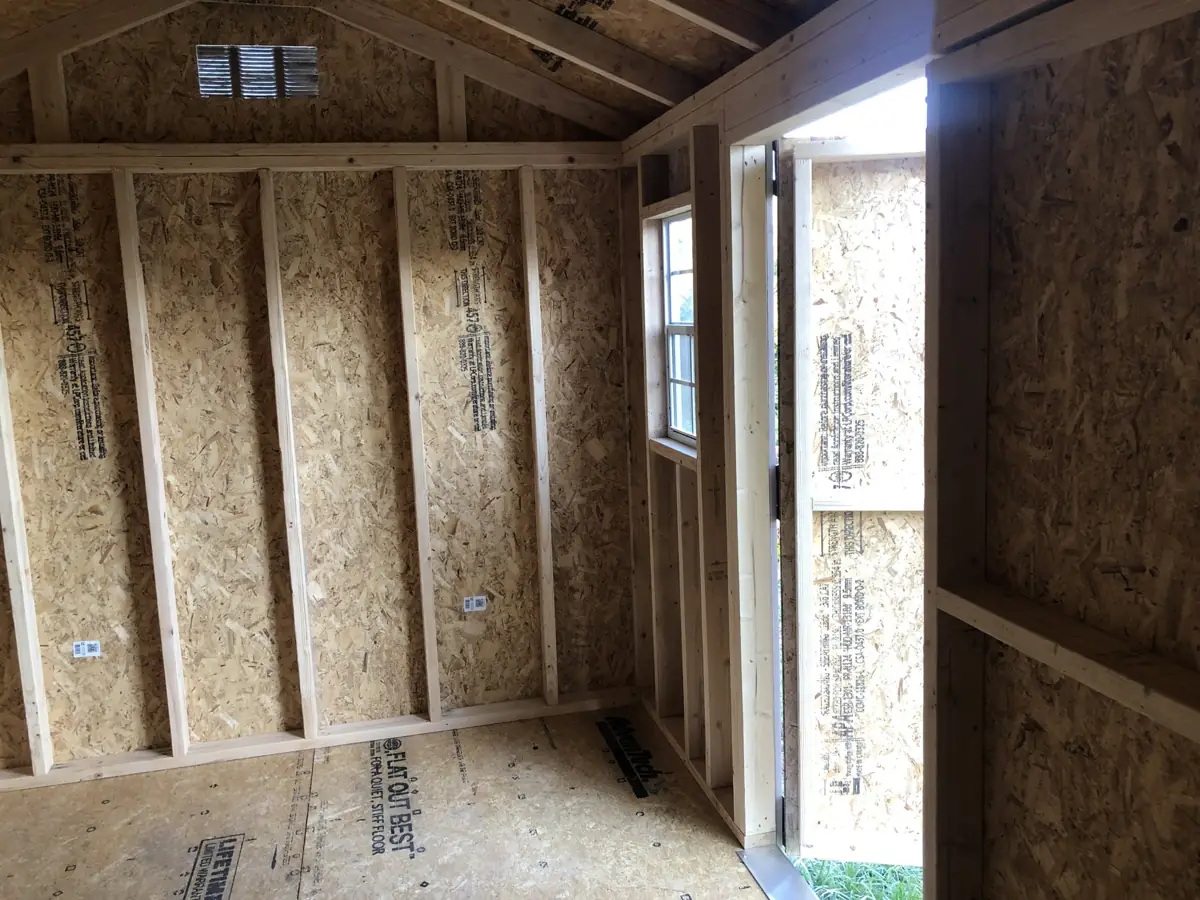 Inside a garden shed: framed walls, OSB sheathing, window and double doors