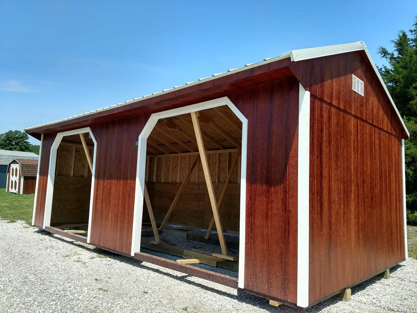 Stained livestock shelter with two open arched bays and a metal roof