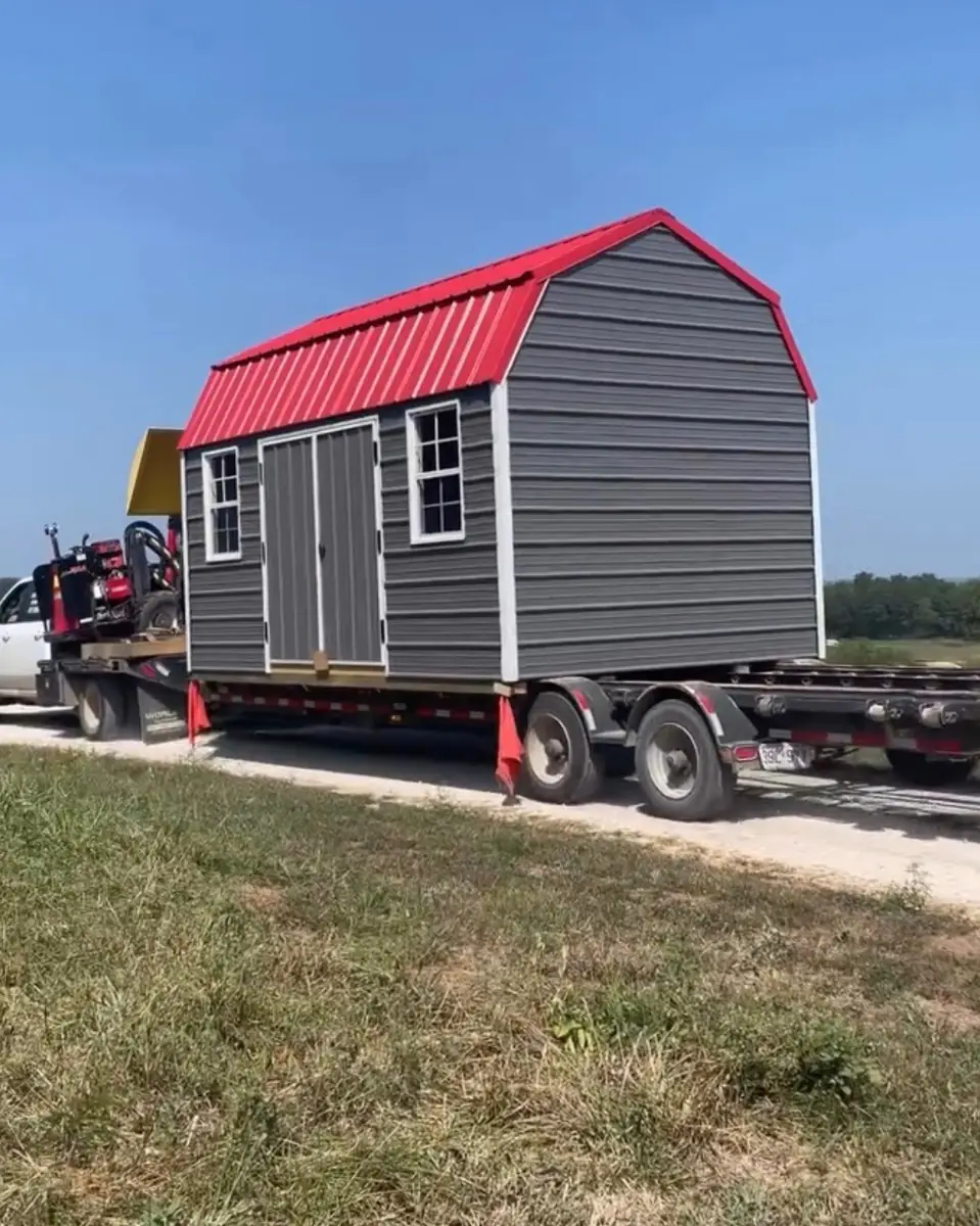 Charcoal lofted barn with a red roof on a trailer, ready for delivery