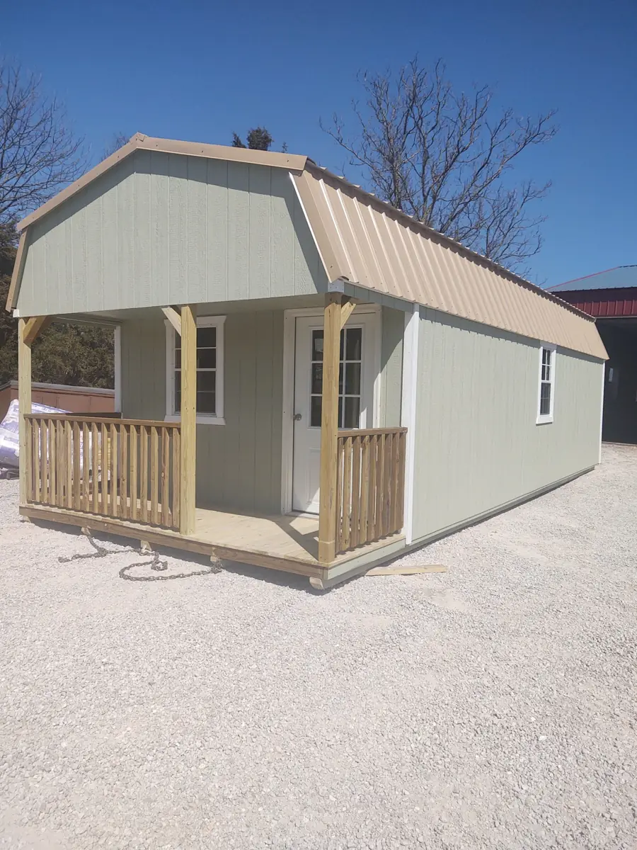 Tan lofted cabin with a barn roof and a covered porch with railings