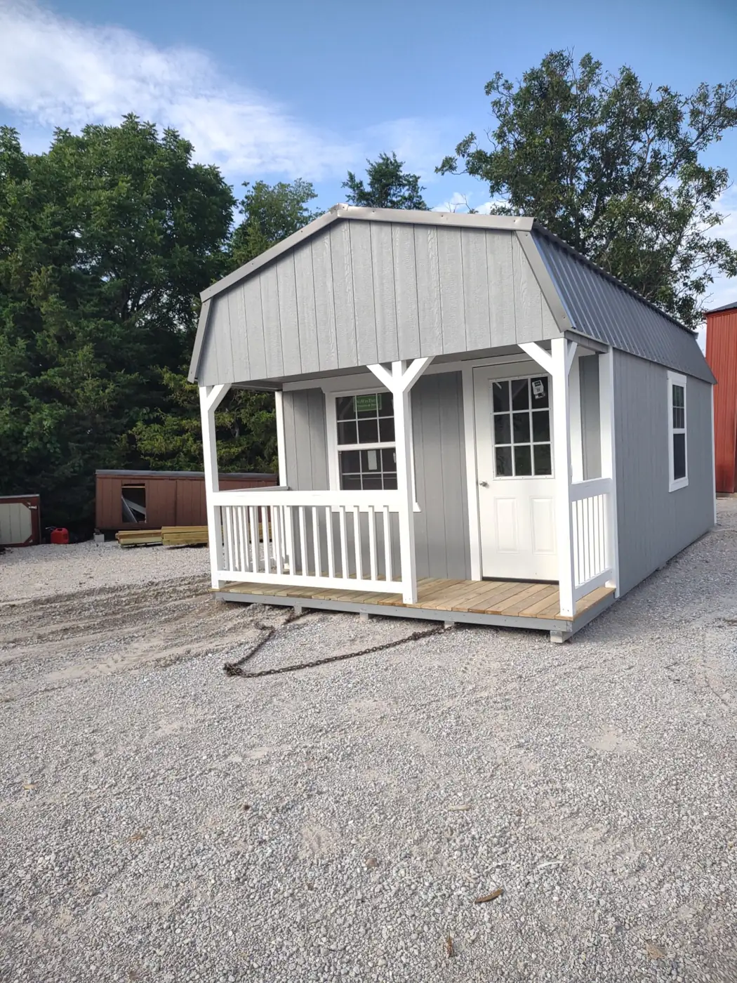 Gray lofted cabin with a barn roof, white porch railing and French door
