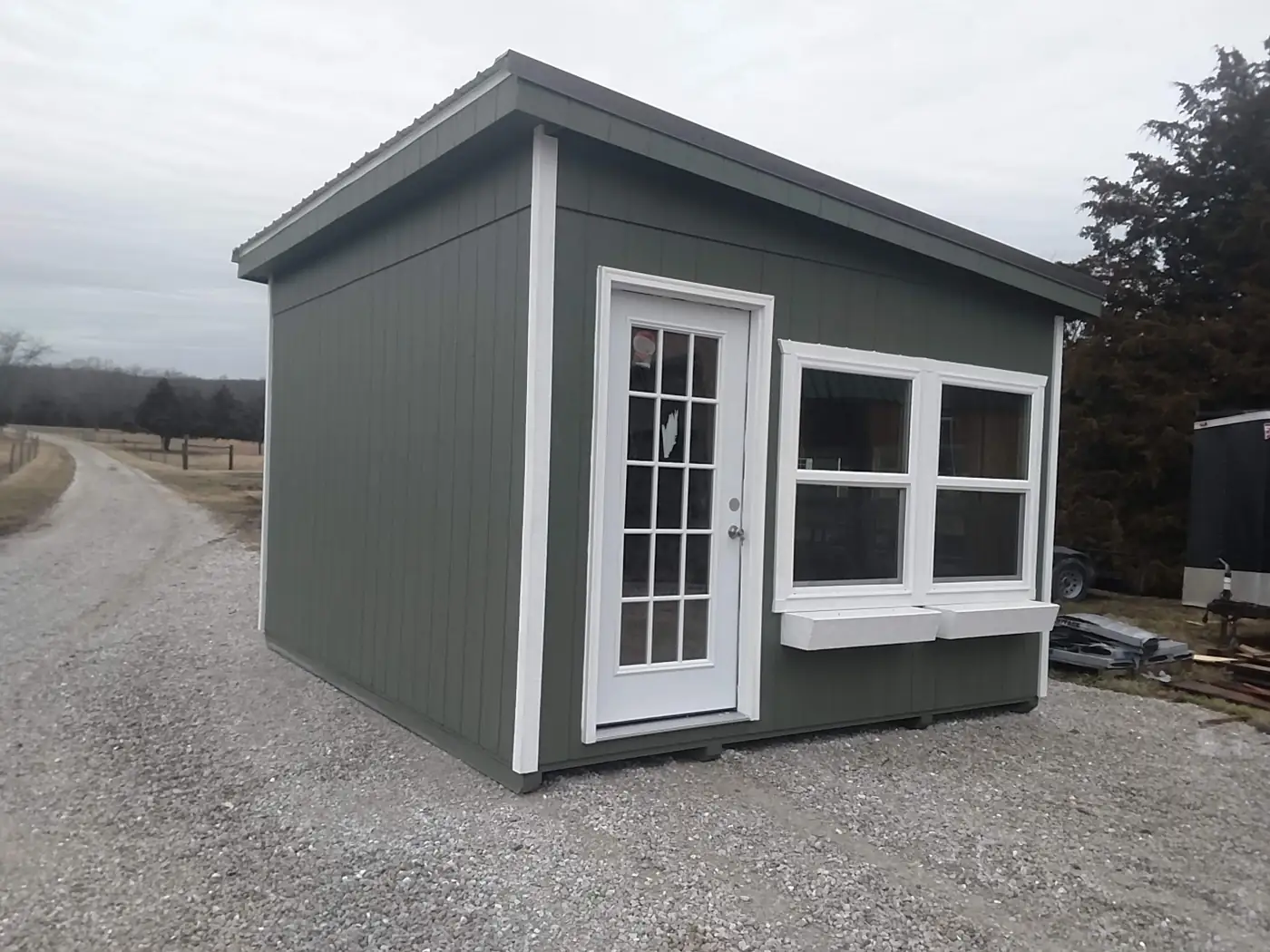 Gray studio cabin with a single-slope roof, a French door and a bank of white windows