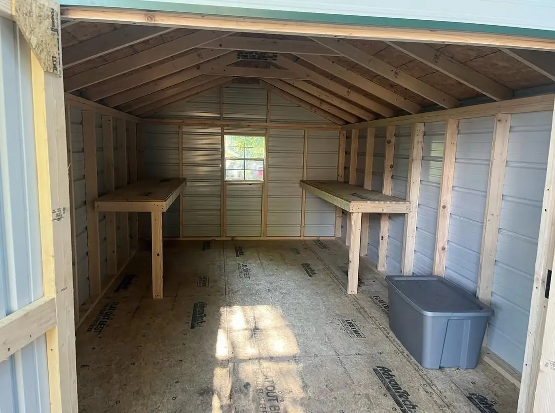 Inside a utility shed with a built-in workbench, shelving and a window